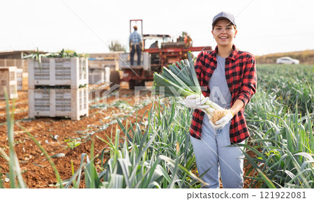 Woman posing with leek crop on field 121922081