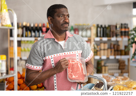 African man choose raw beef entrecote meat for roasting in store African man choose raw beef entrecote meat for roasting in store 121922257
