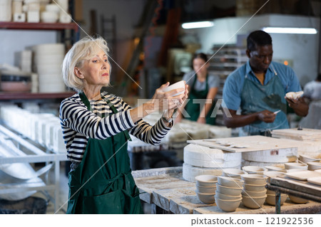 Portrait of positive senior woman holding ceramic cups at workshop Portrait of positive senior woman holding ceramic cups at workshop 121922536
