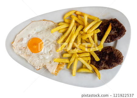 There is food for lunch on plate - two flat cutlets, French fries, fried eggs. There is food for lunch on plate - two flat cutlets, French fries, fried eggs. 121922537