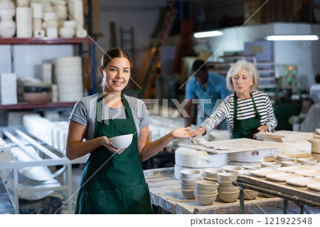 Cheerful young woman ceramist in workshop 121922548