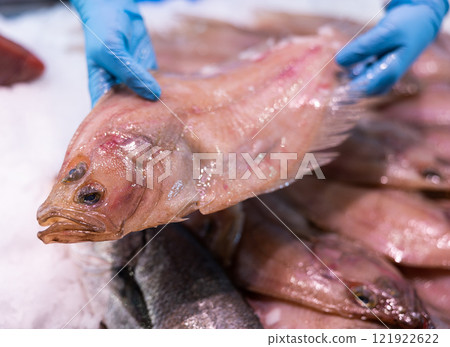 Raw fresh flounder in the hands of seller at fish market 121922622