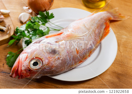 Raw whole red palometa fish with garlic and parsley on desk Raw whole red palometa fish with garlic and parsley on desk 121922658