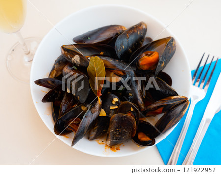Portion of steamed mussels served with bay leaf on plate. Spanish dish mejillon la marinera 121922952