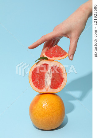 Sliced and whole grapefruit in female hand on blue background 121923690