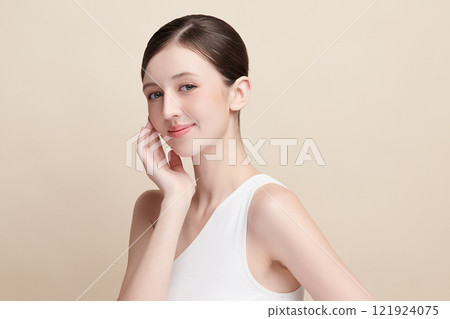 Beautiful young woman with clean fresh skin on beige background, Face care, Facial treatment, Cosmetology, beauty and spa, women portrait. 121924075
