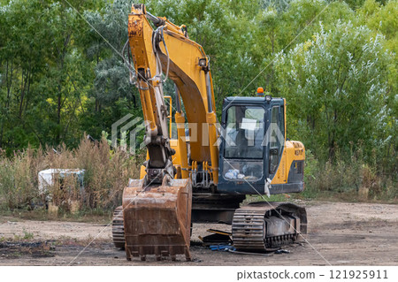 Yellow crawler excavator at a construction site next to a forest Yellow crawler excavator at a construction site next to a forest 121925911