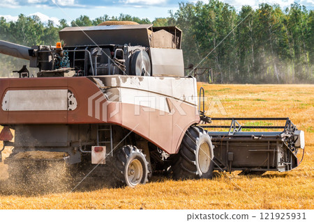 Modern combine harvester working in the field 121925931