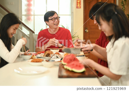 Family gathering for Chinese New Year celebration and enjoying traditional meal together in a festive home Family gathering for Chinese New Year celebration and enjoying traditional meal together in a festive home 121925969