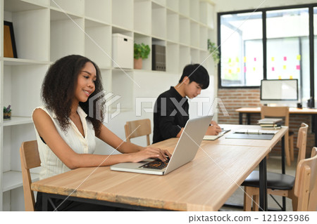 Young businesspeople concentrating on their tasks in a shared office space Young businesspeople concentrating on their tasks in a shared office space 121925986