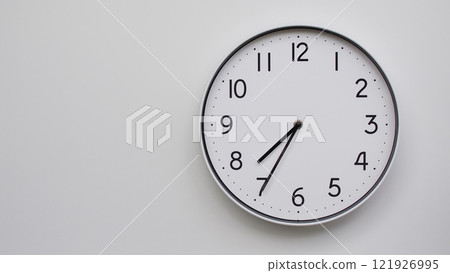 Minimalist Analog Wall Clock with White Face and Simple Black Hands Showing 19.35/07.35 - Ideal for Time Management and Modern Decor Concepts 121926995