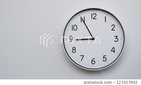 Minimalist Analog Wall Clock with White Face and Simple Black Hands Showing 20.55/08.55 - Ideal for Time Management and Modern Decor Concepts 121927692