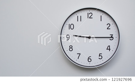 Minimalist Analog Wall Clock with White Face and Simple Black Hands Showing 21.15/09.15 - Ideal for Time Management and Modern Decor Concepts 121927696