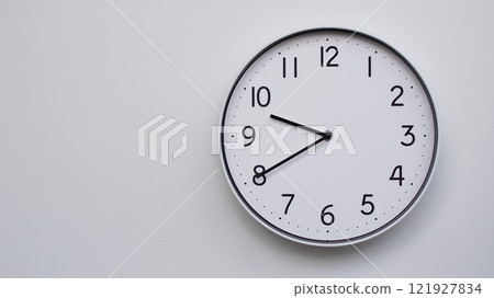 Minimalist Analog Wall Clock with White Face and Simple Black Hands Showing 21.40/09.40 - Ideal for Time Management and Modern Decor Concepts Minimalist Analog Wall Clock with White Face and Simple Black Hands Showing 21.40/09.40 - Ideal for Time Management and Modern Decor Concepts 121927834