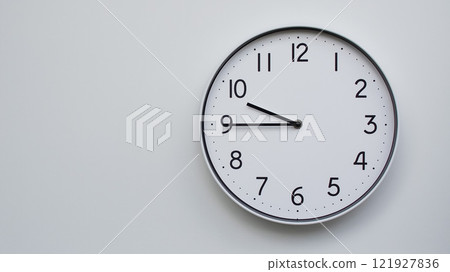 Minimalist Analog Wall Clock with White Face and Simple Black Hands Showing 21.45/09.45 - Ideal for Time Management and Modern Decor Concepts 121927836