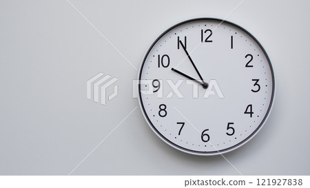 Minimalist Analog Wall Clock with White Face and Simple Black Hands Showing 21.55/09.55 - Ideal for Time Management and Modern Decor Concepts Minimalist Analog Wall Clock with White Face and Simple Black Hands Showing 21.55/09.55 - Ideal for Time Management and Modern Decor Concepts 121927838