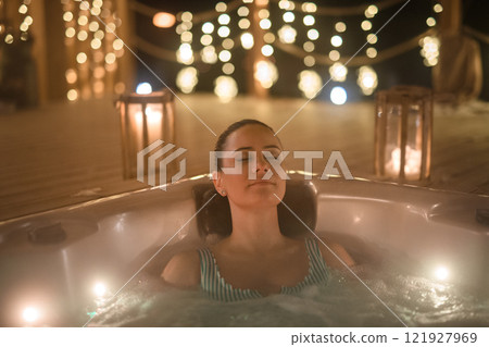 Relaxed woman in hot tub with closed eyes. Single woman celebrating Valentine's Day alone. 121927969