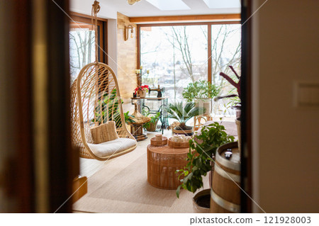The interior of a modern, bright room with large windows and rattan furniture. The interior of a modern, bright room with large windows and rattan furniture. 121928003