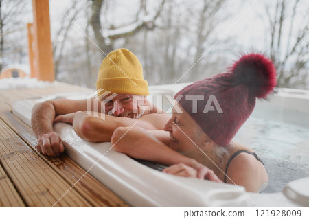 Senior couple bathing in hot tub during cold winter day. Romantic wellness getaway with spa during Valentine's weekend. 121928009