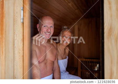Senior couple using small sauna during cold winter day. Spa weekend getaway for elderly people. 121928036