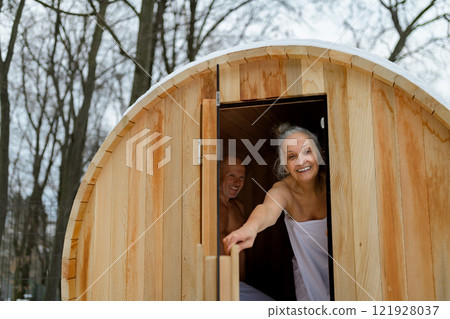 Senior woman entering small sauna. Winter spa weekend getaway for elderly people. Senior woman entering small sauna. Winter spa weekend getaway for elderly people. 121928037