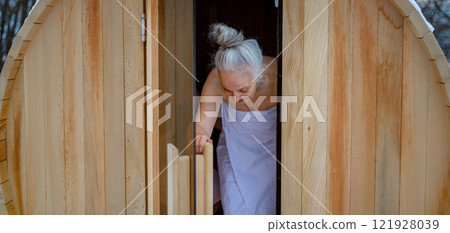 Senior woman entering small sauna. Winter spa weekend getaway for elderly people. 121928039