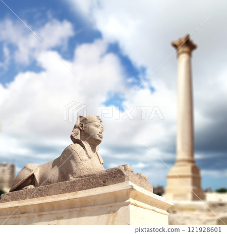 Famous landmark - Serapeum of Alexandria. Sphinx and Pompey's Pillar in Alexandria, Egypt, North Africa. Roman temple Serapeum with Pompey's pillar and sphinx 121928601