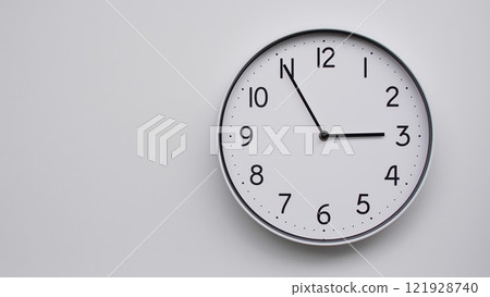 Minimalist Analog Wall Clock with White Face and Simple Black Hands Showing 14.55/02.55 - Ideal for Time Management and Modern Decor Concepts Minimalist Analog Wall Clock with White Face and Simple Black Hands Showing 14.55/02.55 - Ideal for Time Management and Modern Decor Concepts 121928740