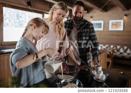 Family making pancakes, preparing sweet breakfast in the morning. Girl mixing pancake batter. Family making pancakes, preparing sweet breakfast in the morning. Girl mixing pancake batter. 121928886
