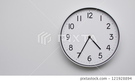 Minimalist Analog Wall Clock with White Face and Simple Black Hands Showing 16.35/04.35 - Ideal for Time Management and Modern Decor Concepts 121928894