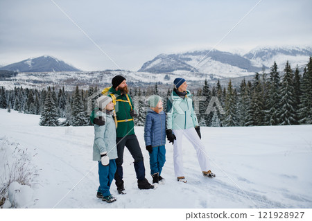Family walking across snowy winter nature, holding by hands. Family winter vacation in snowy mountains. Family walking across snowy winter nature, holding by hands. Family winter vacation in snowy mountains. 121928927