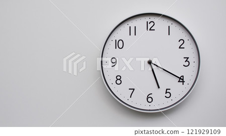 Minimalist Analog Wall Clock with White Face and Simple Black Hands Showing 17.20/05.20 - Ideal for Time Management and Modern Decor Concepts 121929109