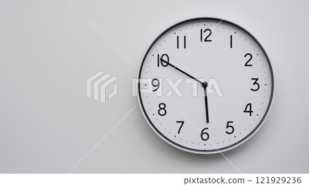 Minimalist Analog Wall Clock with White Face and Simple Black Hands Showing 17.50/05.50 - Ideal for Time Management and Modern Decor Concepts 121929236