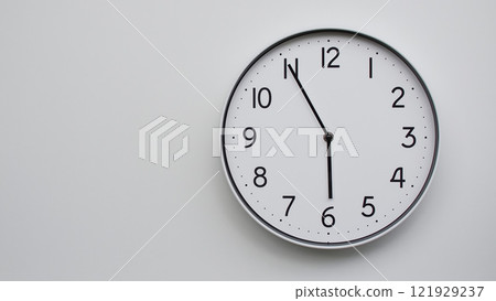 Minimalist Analog Wall Clock with White Face and Simple Black Hands Showing 17.55/05.55 - Ideal for Time Management and Modern Decor Concepts Minimalist Analog Wall Clock with White Face and Simple Black Hands Showing 17.55/05.55 - Ideal for Time Management and Modern Decor Concepts 121929237