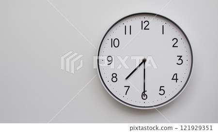Minimalist Analog Wall Clock with White Face and Simple Black Hands Showing 19.30/07.30 - Ideal for Time Management and Modern Decor Concepts 121929351