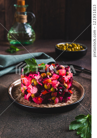Traditional beetroot salad with boiled vegetables and pickles on a plate on the table vertical view 121931813