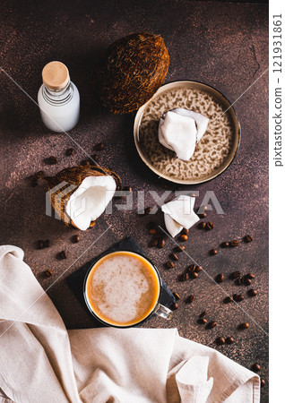 Cup of iced coconut coffee, coconut pulp and coffee beans on table top and vertical view Cup of iced coconut coffee, coconut pulp and coffee beans on table top and vertical view 121931861