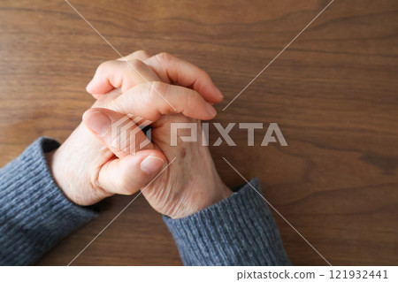 Hands of a senior woman folding her hands at a table 121932441