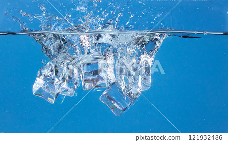 Falling ice cubes in motion with splashing water, creating air bubbles scatter around, blue background isolated. Ice cubes fall into water with air bubbles Falling ice cubes in motion with splashing water, creating air bubbles scatter around, blue background isolated. Ice cubes fall into water with air bubbles 121932486
