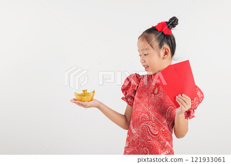 Chinese New Year. Happy Asian Chinese kid girl smile wear red traditional cheongsam qipao dress holding angpao red packet monetary gift and gold ingot isolated on white 121933061