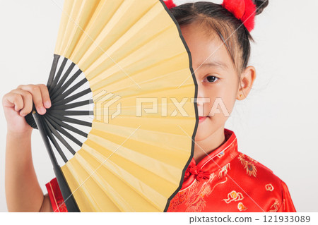 Happy child in a red cheongsam with a golden fan, smiling brightly. A perfect representation of Chinese New Year celebrations, blending tradition and joy. Isolated on a white background Happy child in a red cheongsam with a golden fan, smiling brightly. A perfect representation of Chinese New Year celebrations, blending tradition and joy. Isolated on a white background 121933089