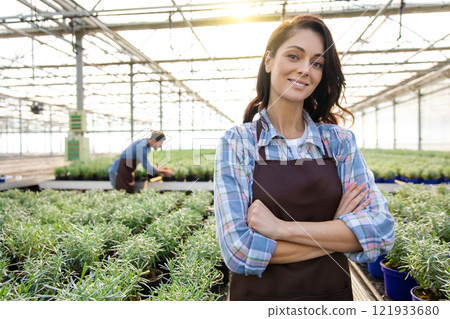 Smiling dark-haired woman in apron in a glasshouse 121933680