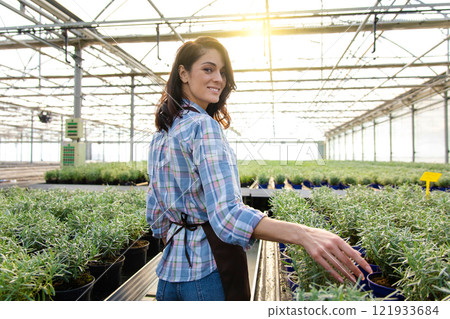 Smiling pretty female glasshouse worker at her working place 121933684