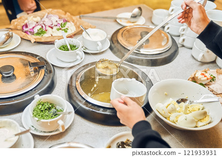 Buffet in the restaurant. Hands put a ladle of liquid soup. A delicious hot dish in cups with a variety of fresh vegetables and tender meat, simmered in a spicy broth. High quality photo Buffet in the restaurant. Hands put a ladle of liquid soup. A delicious hot dish in cups with a variety of fresh vegetables and tender meat, simmered in a spicy broth. High quality photo 121933931