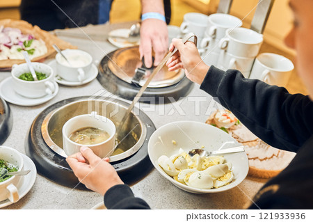 A man pours delicious soup from a large pot into a bowl. Buffet in the restaurant. With space to copy. High quality photo A man pours delicious soup from a large pot into a bowl. Buffet in the restaurant. With space to copy. High quality photo 121933936
