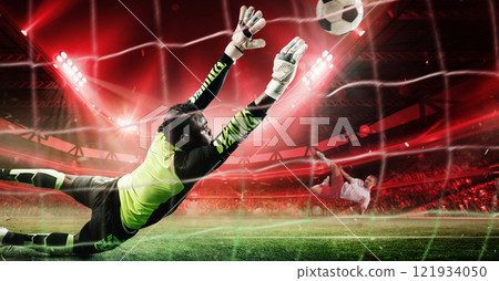Goalkeeper in vibrant neon uniform diving mid-air to block powerful penalty shot during intense soccer game in 3D stadium filled with dramatic red lighting. 121934050