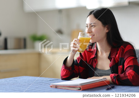 Happy asian student drinking orange juice for breakfast 121934206