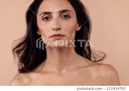 Studio portrait of a charming brunette woman in a white top with beautiful wavy hair 121934705