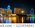 Night view of a hotel in central Singapore from Merlion Park with the moon hiding behind the clouds 121934841