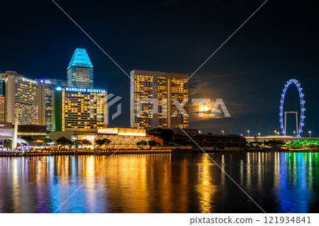 Night view of a hotel in central Singapore from Merlion Park with the moon hiding behind the clouds 121934841
